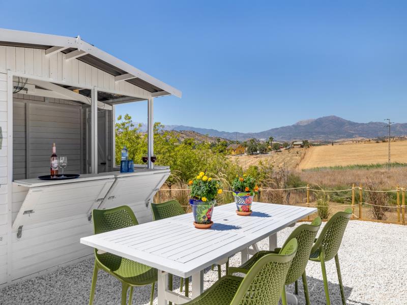 Outdoor bar with open shutters and a table set with flowers