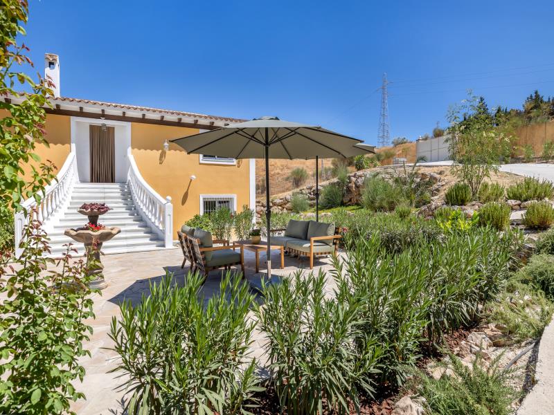 Villa entrance with stone fountain and garden sofa under a parasol