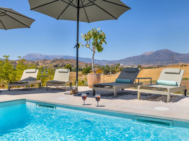 Sun loungers by the pool with wine glasses and mountain views