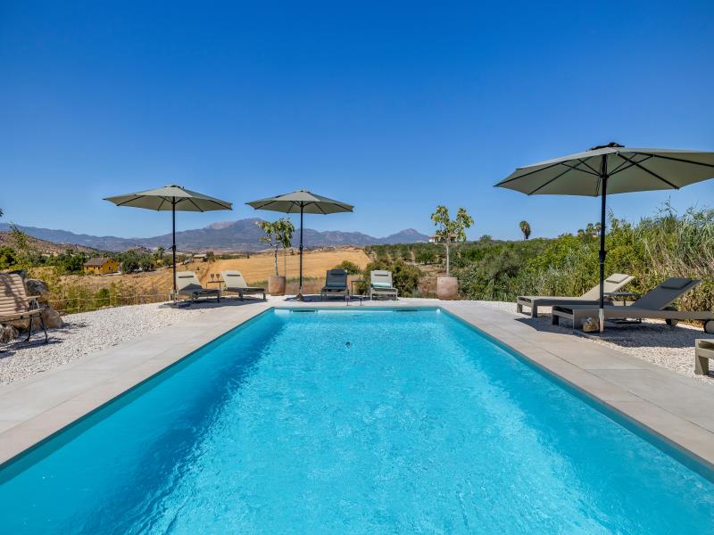 Rectangular pool with parasols and loungers overlooking the countryside