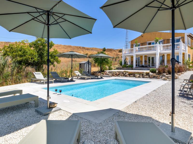 Pool with wine glasses and a view of the villa's double balcony